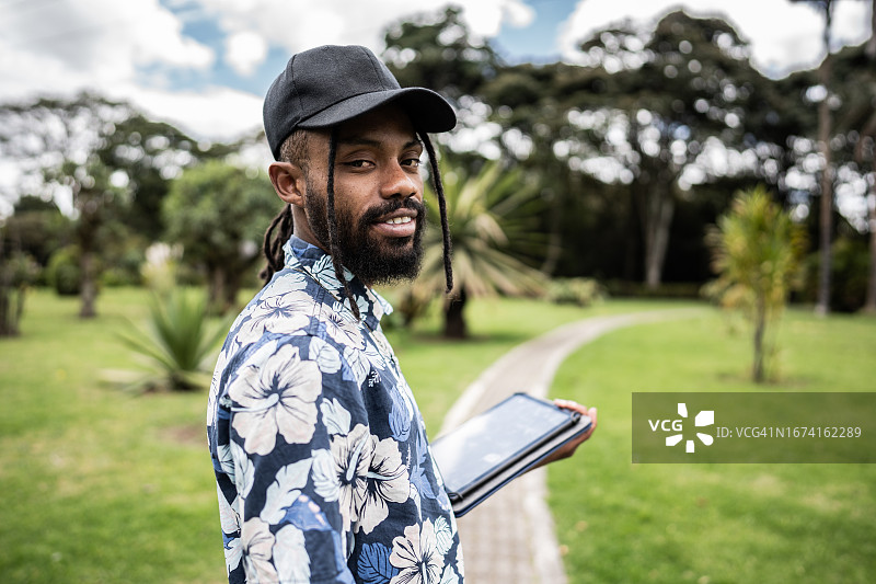 年轻男子在户外手持平板电脑的肖像图片素材