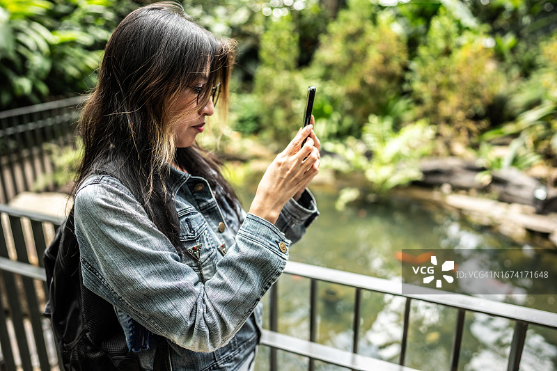 中年女人在植物园考察期间拍照或拍摄图片素材
