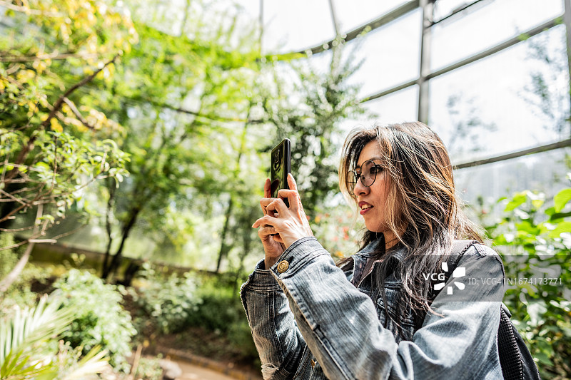 中年女人在植物园考察期间拍照或拍摄图片素材