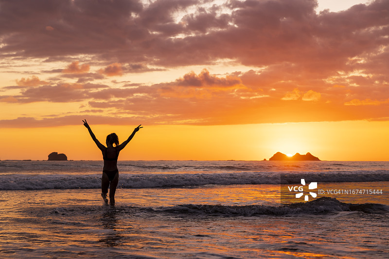 一位女士在日落时走向大海图片素材