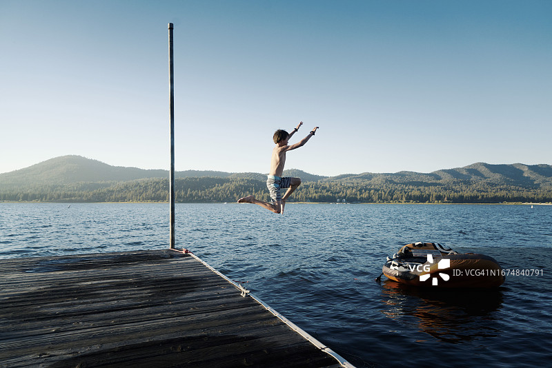 男孩从码头上跳入湖中图片素材
