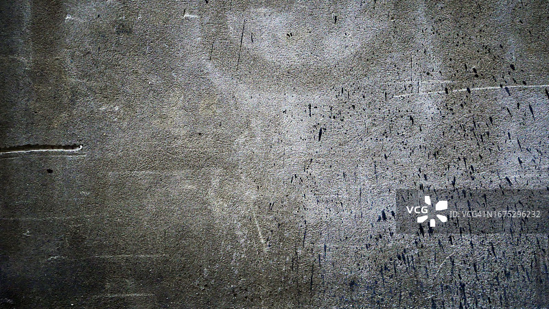 阳光与阴影之间：加拿大魁北克蒙特利尔风化的灰色混凝土墙特写，带有黑色油漆滴图片素材