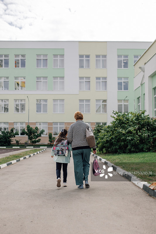 快乐女学生牵手慈祥祖母走向学校的背影图片素材