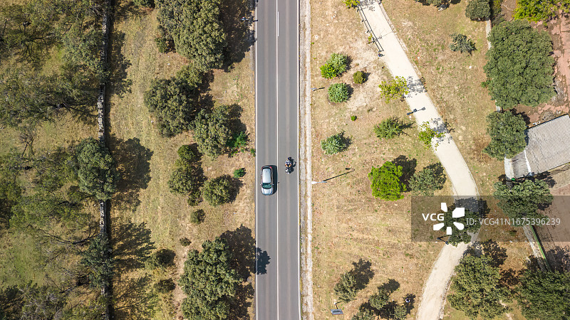 道路两侧植被茂盛，汽车和摩托车穿梭其中航拍视角图片素材