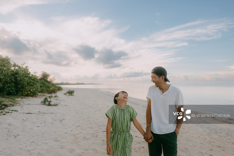 父女在日落时分的海滩上散步图片素材