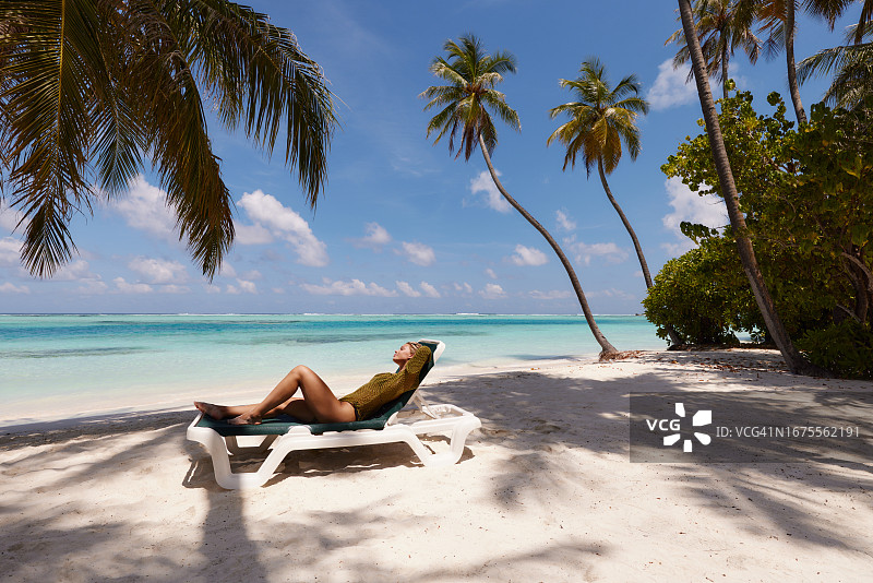 笑容满面的女人在沙滩的躺椅上放松图片素材