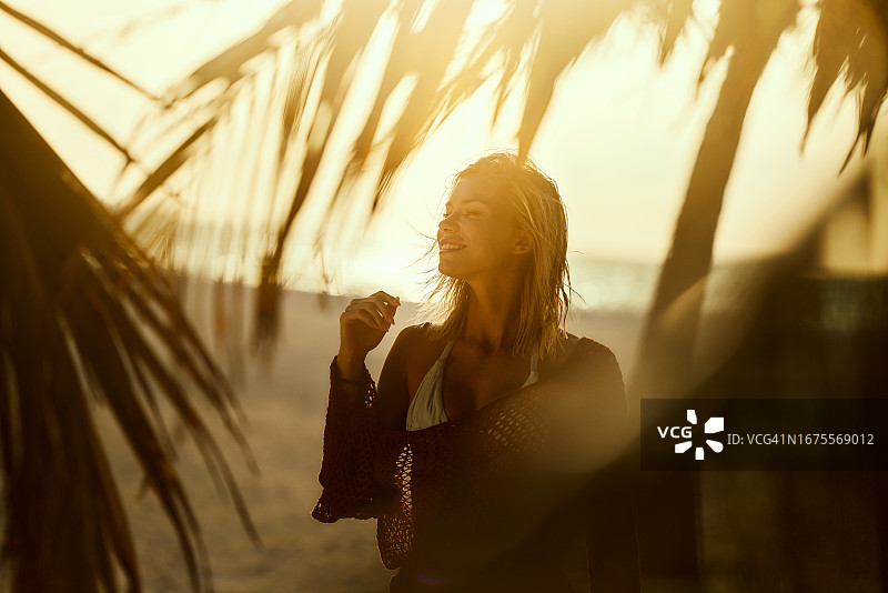 快乐的女人在日落时分享受海滩美景图片素材