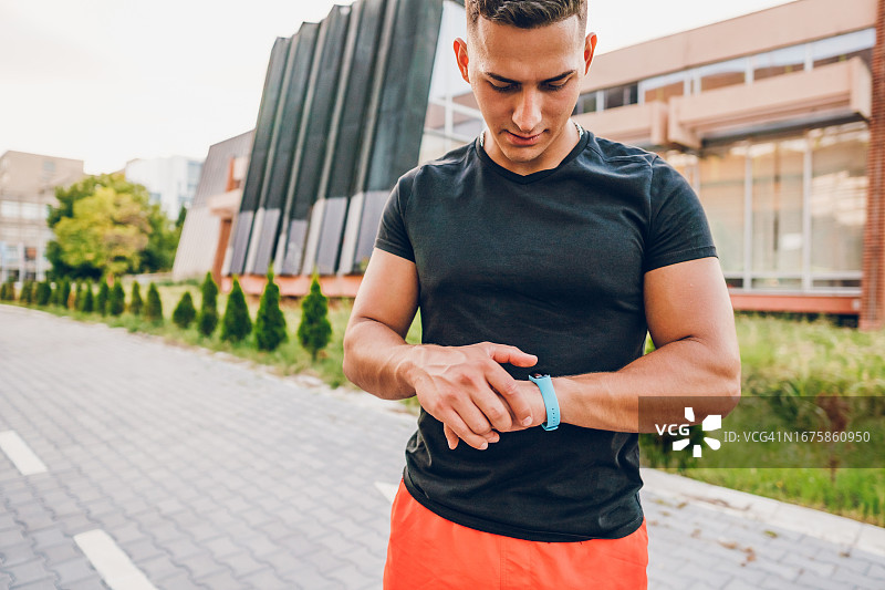 运动员在户外锻炼后查看健身追踪器上的运动数据图片素材