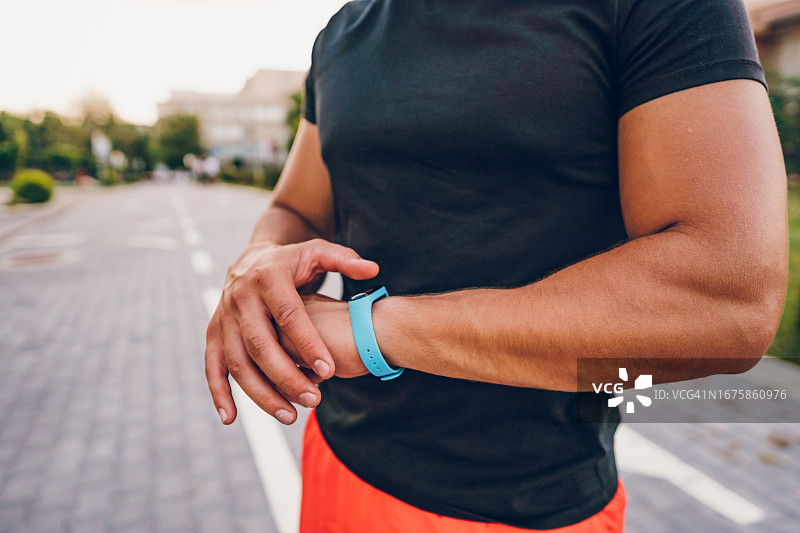 运动员在户外锻炼后查看健身追踪器上的运动数据图片素材
