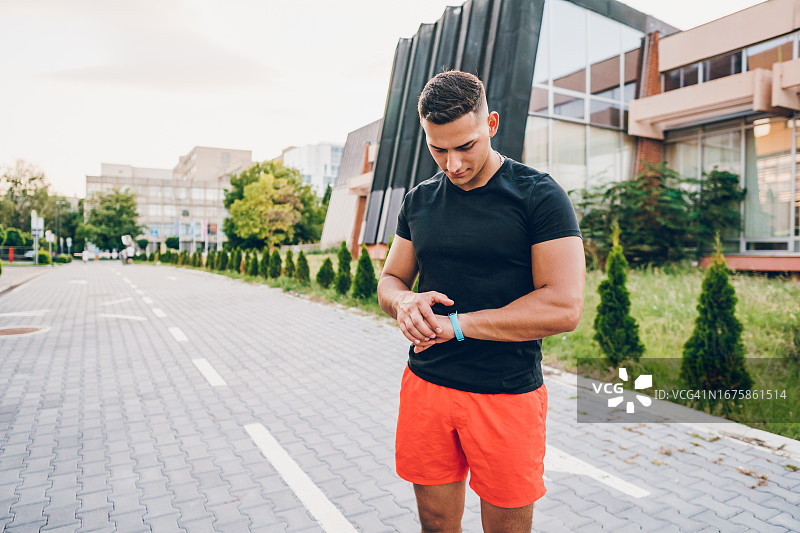运动员在户外锻炼后查看健身追踪器上的运动数据图片素材
