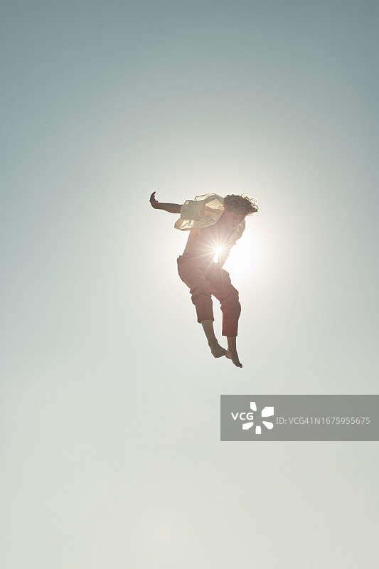 衬衫敞开的逆光男人跳跃在空中图片素材