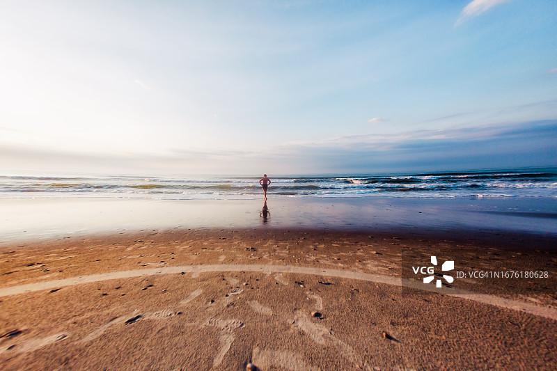 日出时独自在海滩上的青少年女孩图片素材