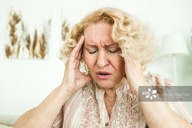 头痛欲裂、按着太阳穴的年长女人图片素材