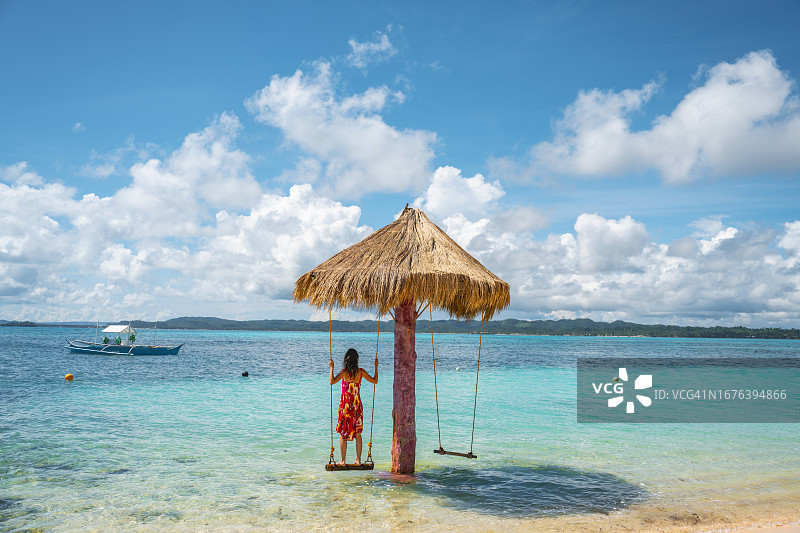 站在热带水域秋千上的女人图片素材