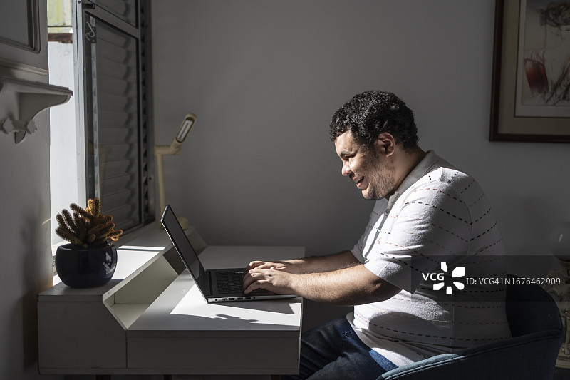在卧室使用笔记本的年轻拉丁裔男孩图片素材