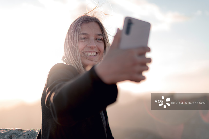 在山顶俯瞰处微笑自拍，捕捉在山中日落的幸福图片素材