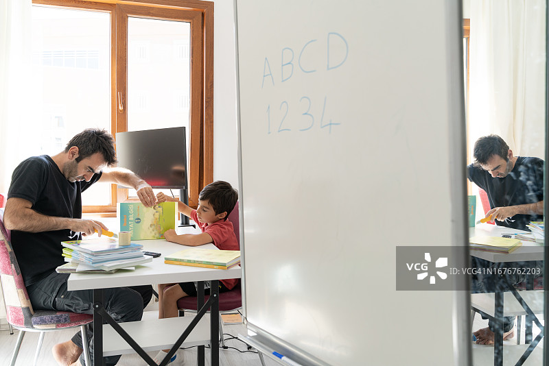 父亲在书桌旁为儿子整理书籍图片素材