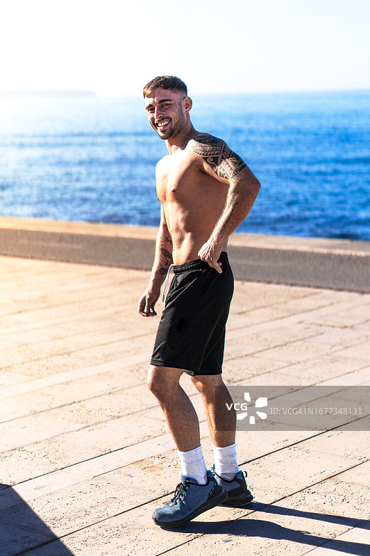 有纹身的健壮年轻男人在街上锻炼后休息，看着镜头。图片素材