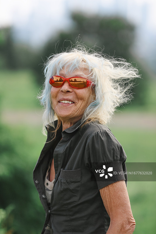 留着蓝色头发、穿着休闲卡其色裤装的时髦老年妇女在户外散步：健康生活方式，非城市风光图片素材