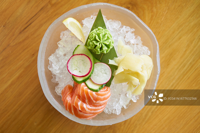 餐厅冰盘上的寿司和蔬菜（三文鱼、萝卜、黄瓜、芥末和姜片）图片素材