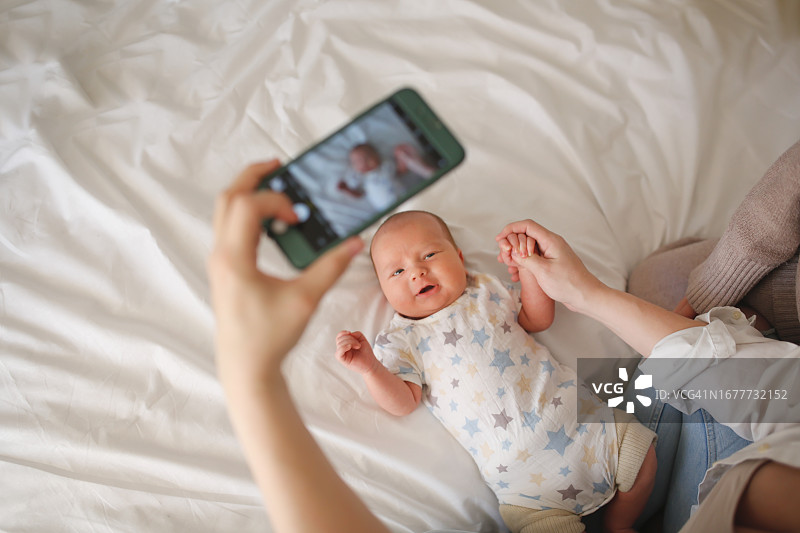 母亲用智能手机给宝宝拍照图片素材