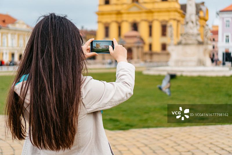 年轻女子在蒂米什瓦拉市中心广场拍照图片素材