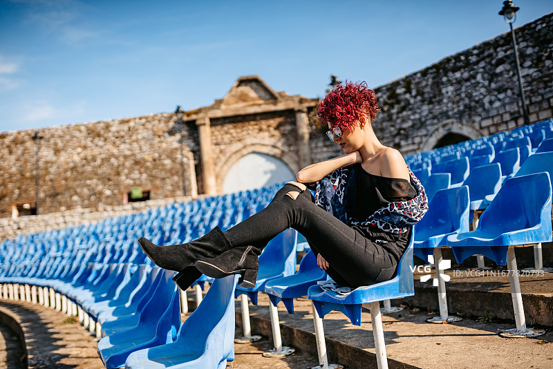 坐在空旷户外剧院的年轻女人图片素材