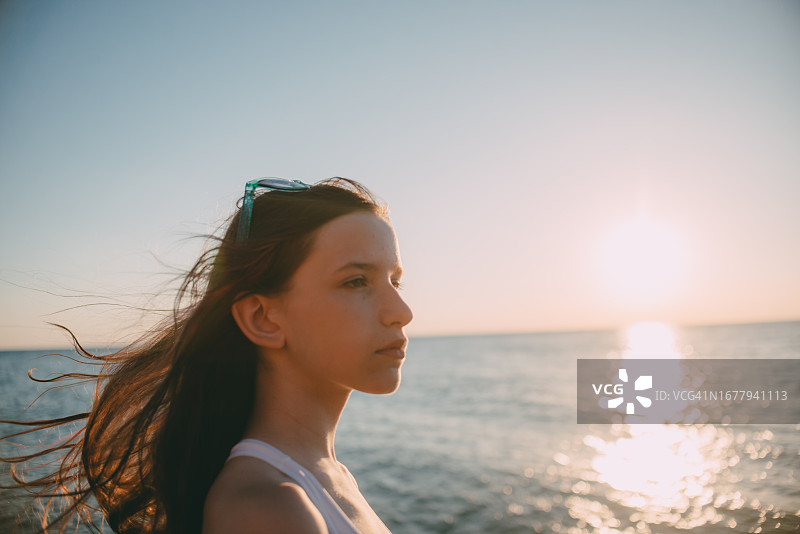 以日落时分为背景的青少年女孩肖像图片素材