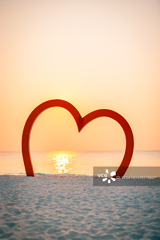 日落时沙滩上的木制心形标志，浪漫蜜月旅行图片素材