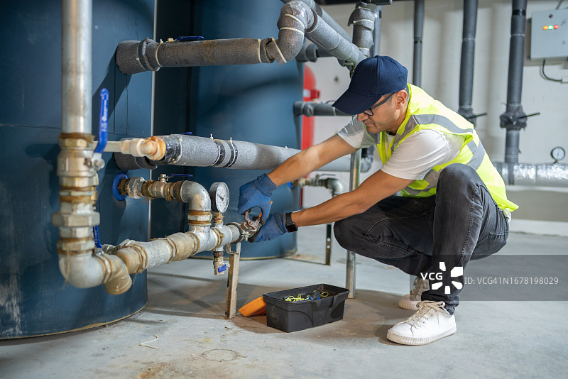 男工程师在地下室检查锅炉系统图片素材