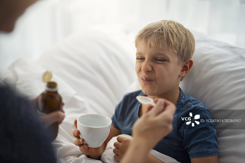 母亲给小男孩喂难吃的药图片素材