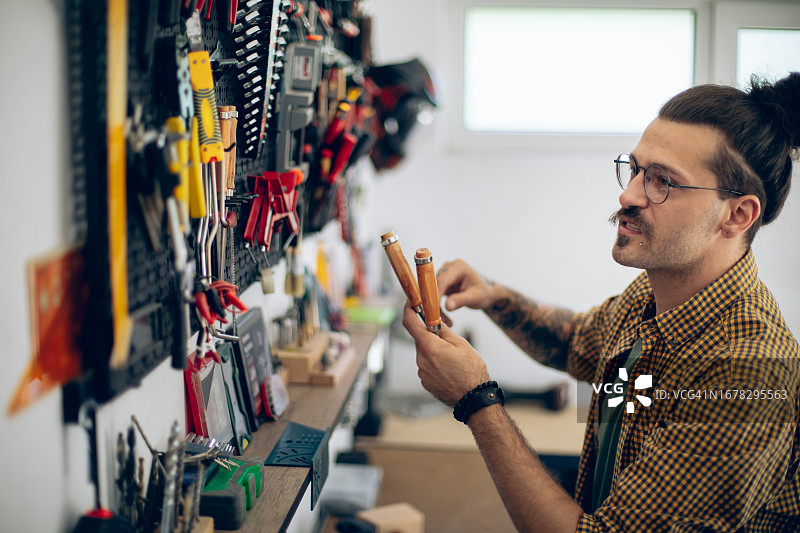 工匠从墙壁收纳架上取下工具图片素材