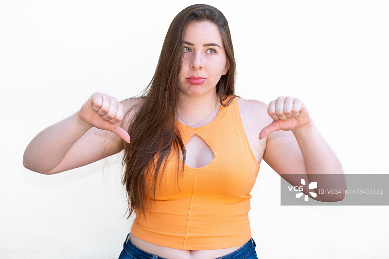 拉丁裔女子看着镜头，竖起大拇指向下。图片素材