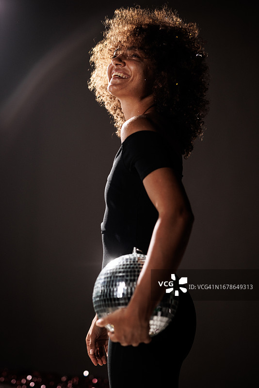 年轻女人手拿迪斯科球，背景为深灰色图片素材