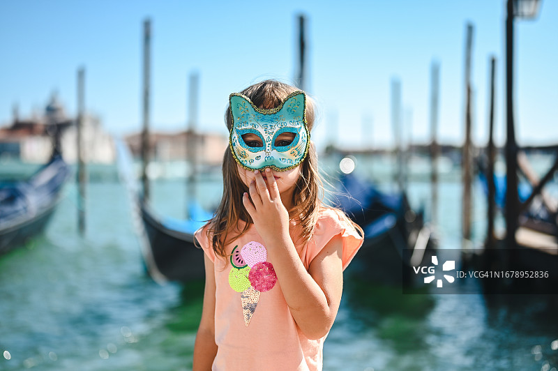 在威尼斯大运河前戴着狂欢节面具的小女孩图片素材