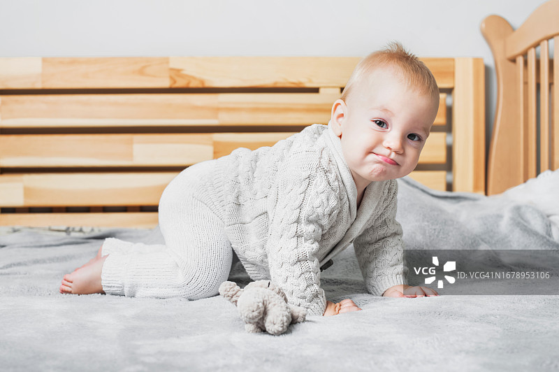 可爱的9个月大的宝宝穿着针织衣服在床上图片素材