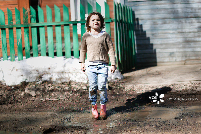 飞溅的春天：快乐的孩子跳过泥泞的水坑图片素材