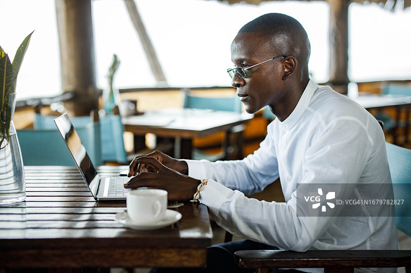 在咖啡馆用笔记本电脑工作的黑人男商人图片素材