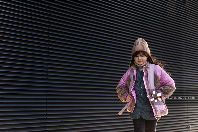 寒冷冬日城市里，背着背包的漂亮小女孩肖像图片素材