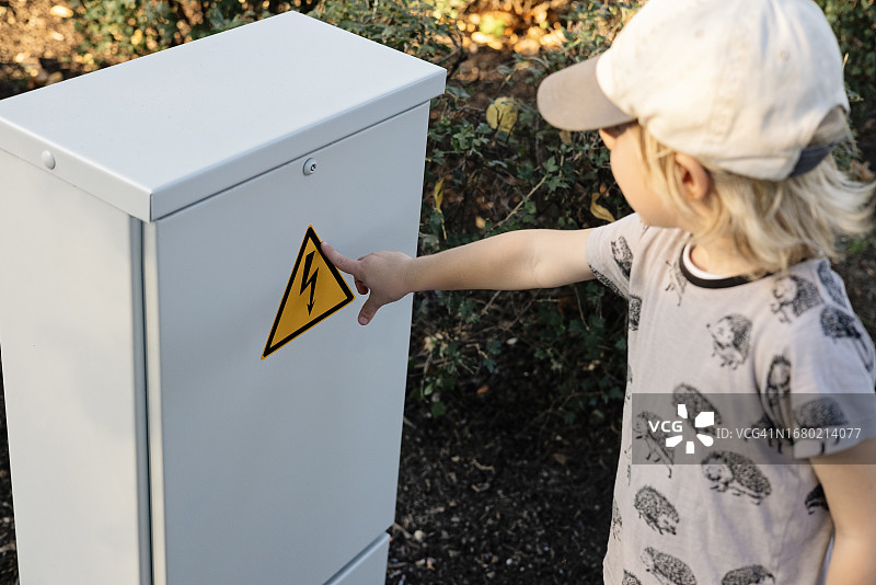 儿童在带警告标志的电气设备箱旁图片素材
