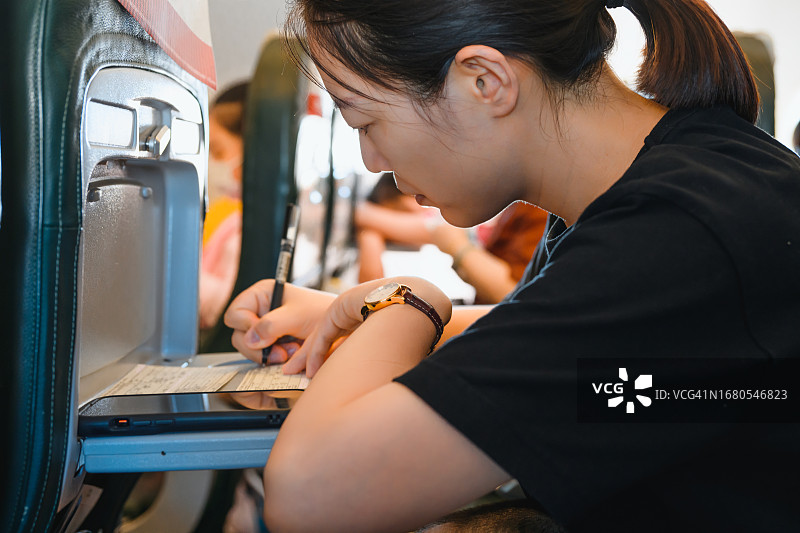 乘飞机入境，女人填写移民信息卡图片素材