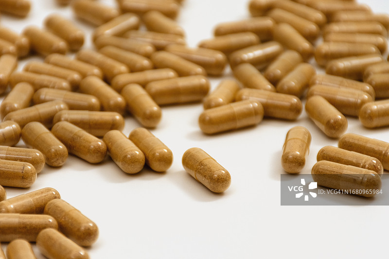 白色背景上透明医用胶囊橙色粉末图片素材