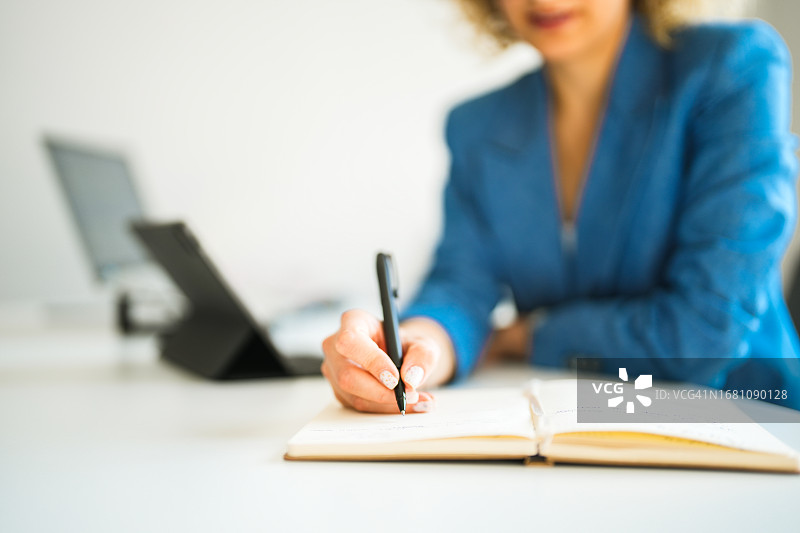 身穿蓝色夹克的卷发女商人办公室做笔记特写图片素材