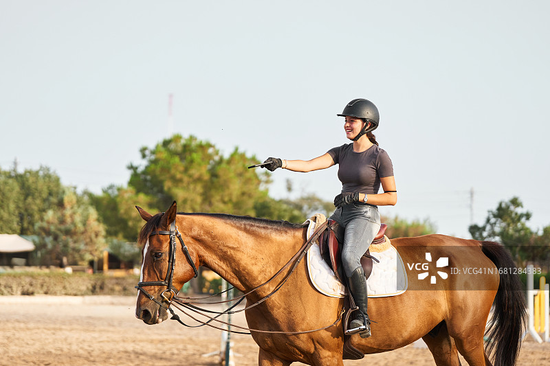 年轻女子在骑术学校骑马图片素材