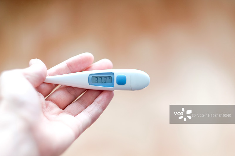 手中37.3度的电子温度计特写图片素材