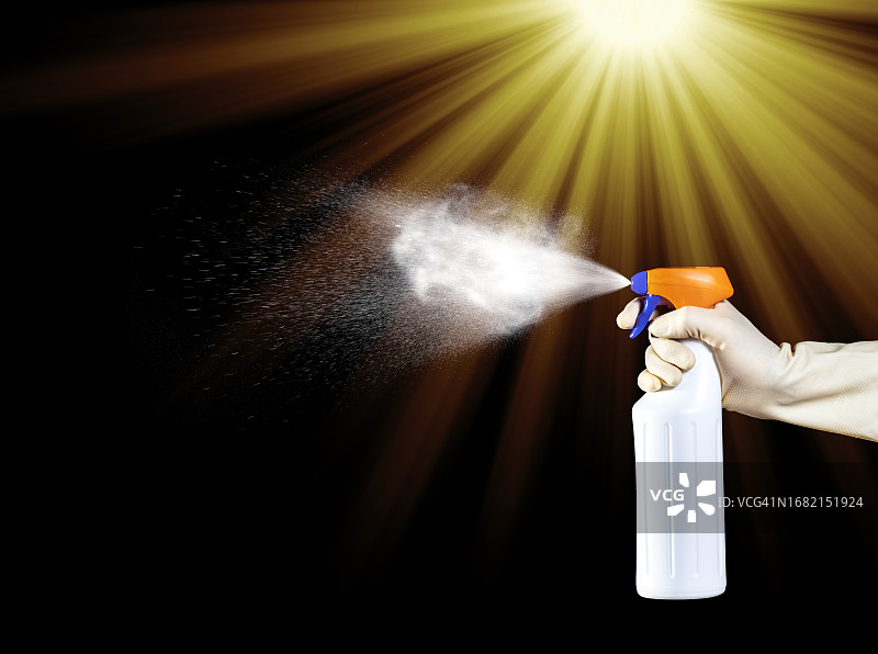 一个人在黑背景上用消毒喷雾瓶的手图片素材