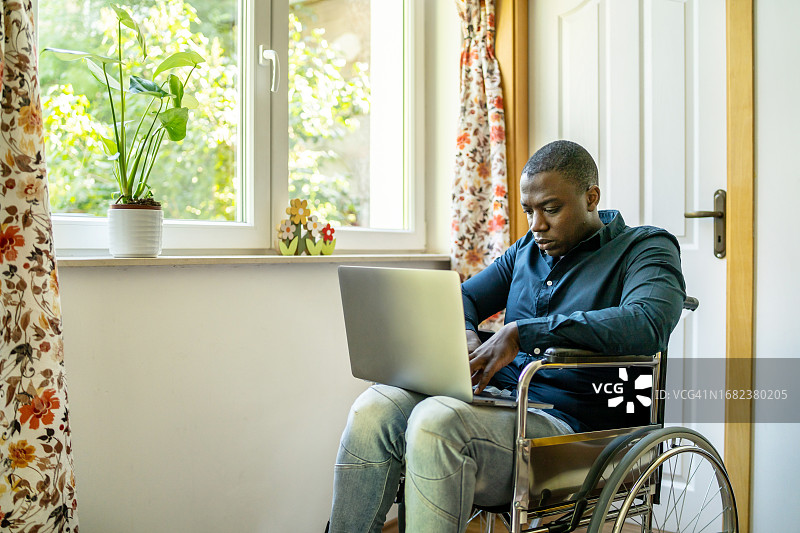 坐在轮椅上用笔记本电脑打字的人图片素材