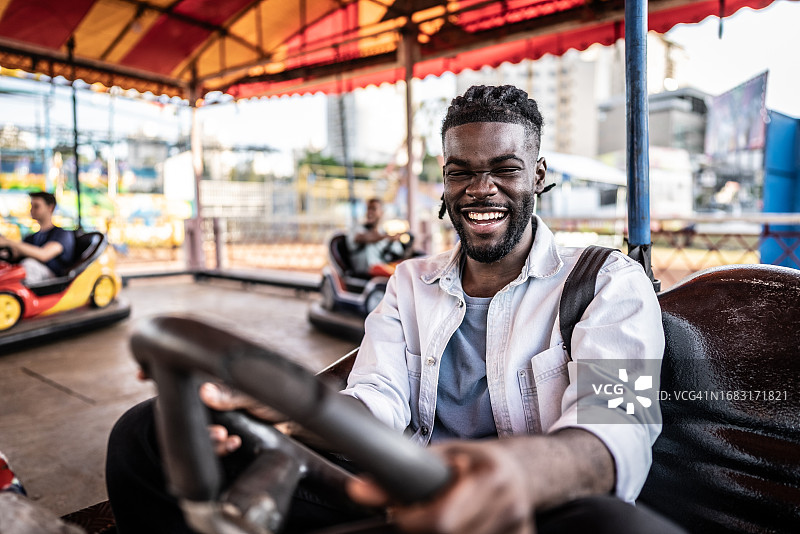 年轻男人在游乐园里玩碰碰车图片素材