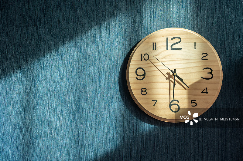 挂在蓝色壁纸上的木制时钟图片素材