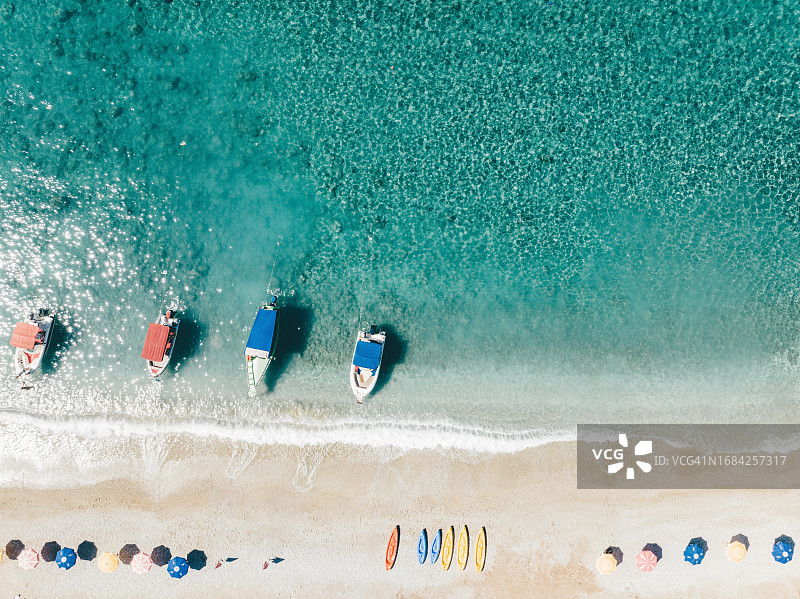 海滩上的彩色雨伞、皮划艇和船只顶视图图片素材